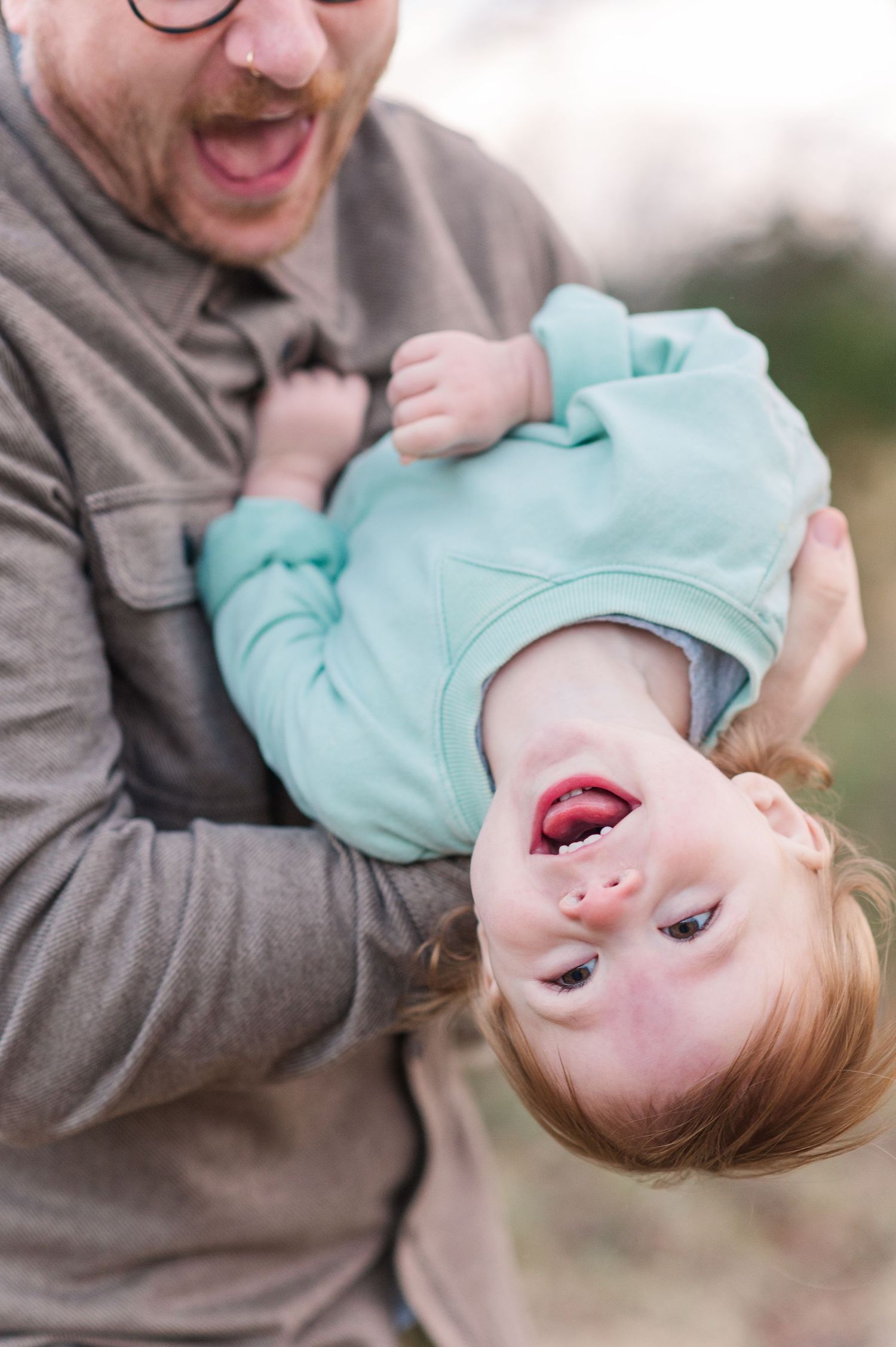 A series of playful photos showing a small child in a mint green shirt being held upside down and laughing.