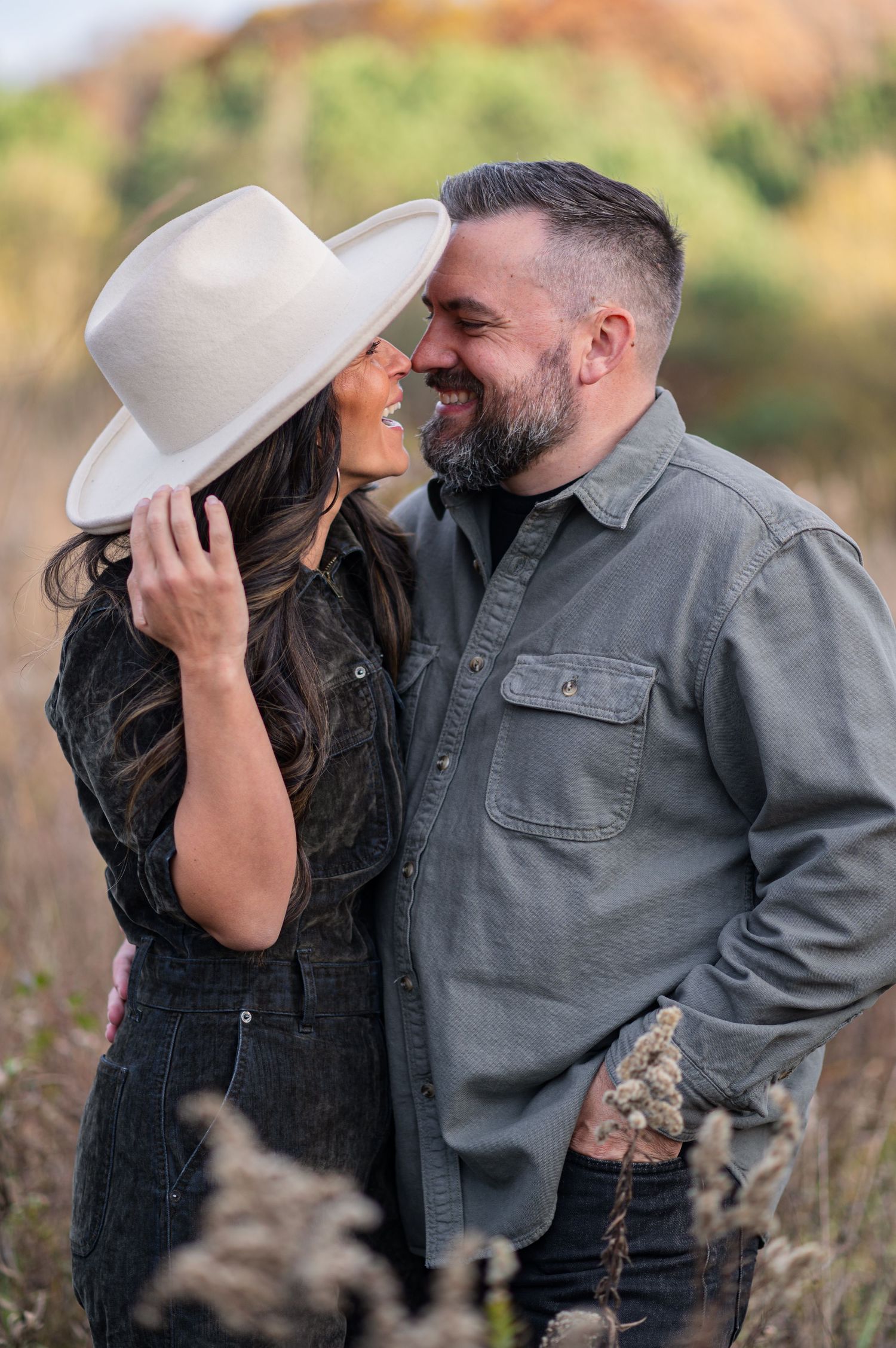 A romantic couple shares intimate moments in a field wearing casual attire and a white hat.