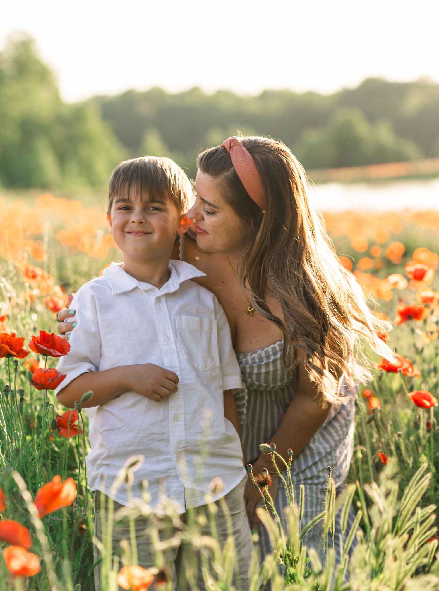 Beautiful family photoshoot in a vibrant red poppy field at sunset.
