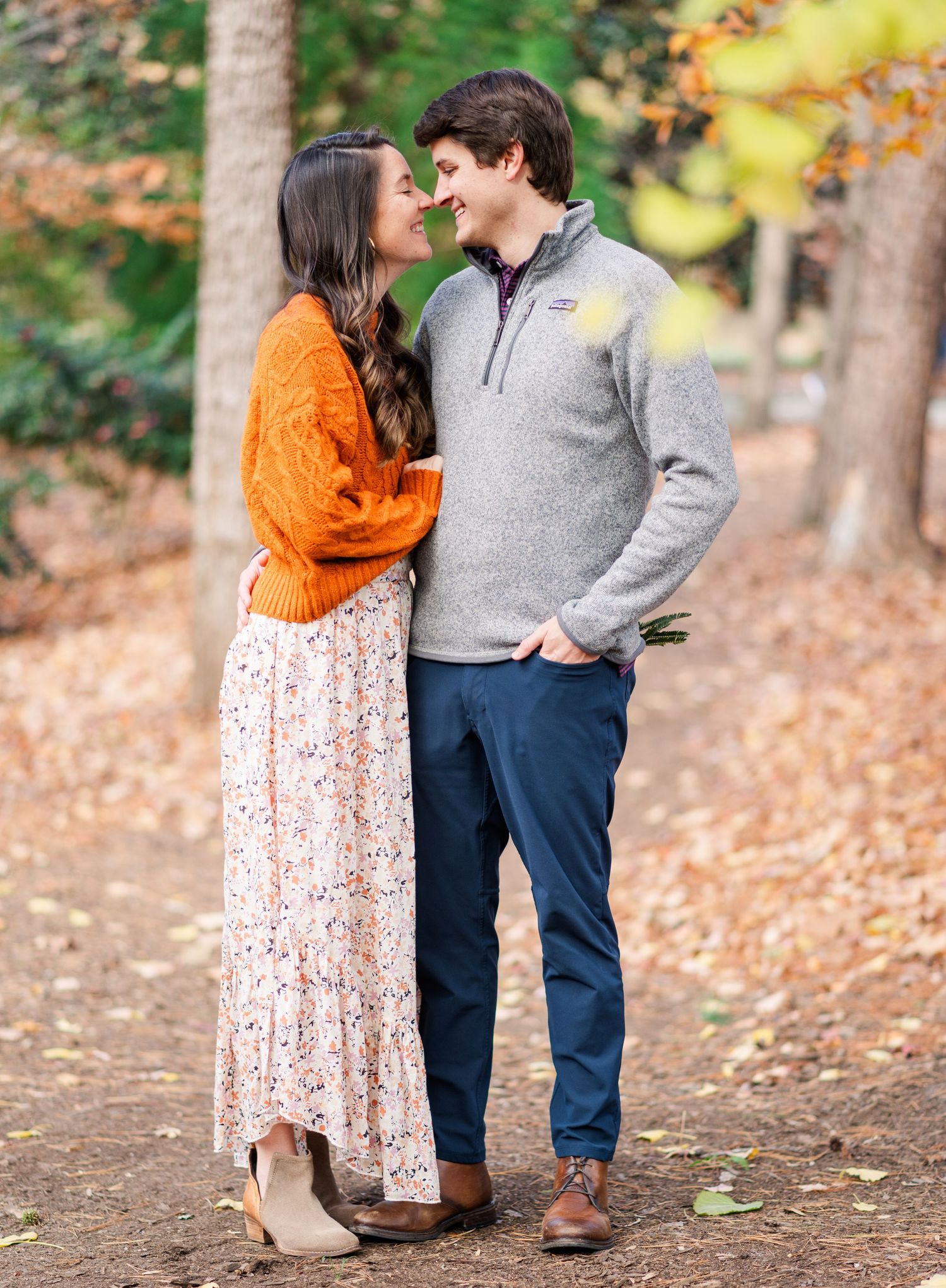 Couple in autumn attire shares romantic moments among fallen leaves.