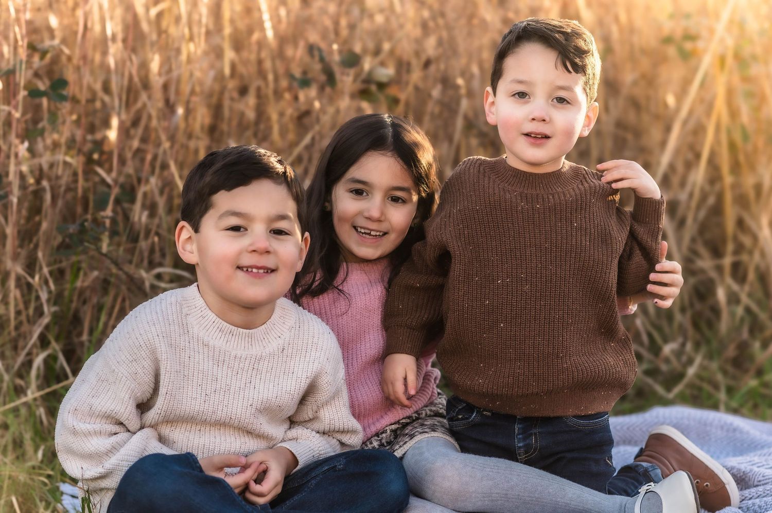 Family portrait session in golden field during sunset with natural warm lighting.