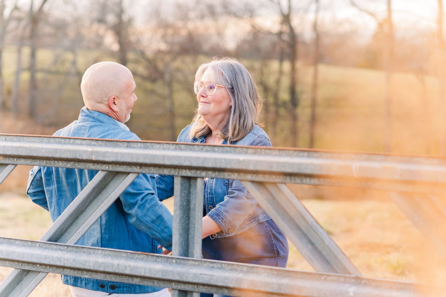 A couple shares a tender moment on a wooden dock during golden hour sunset.