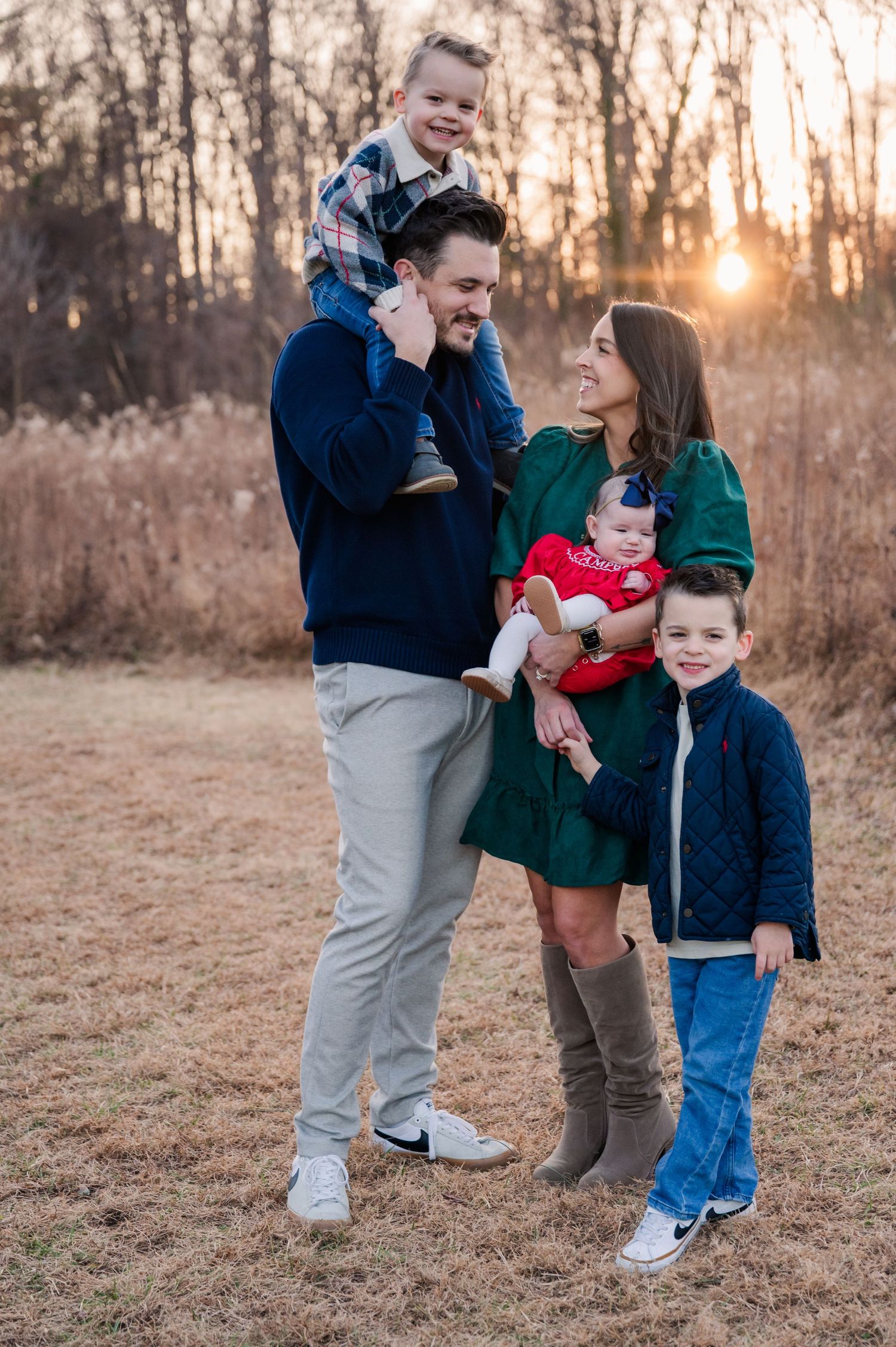 A family of five poses together outdoors during golden hour at sunset.