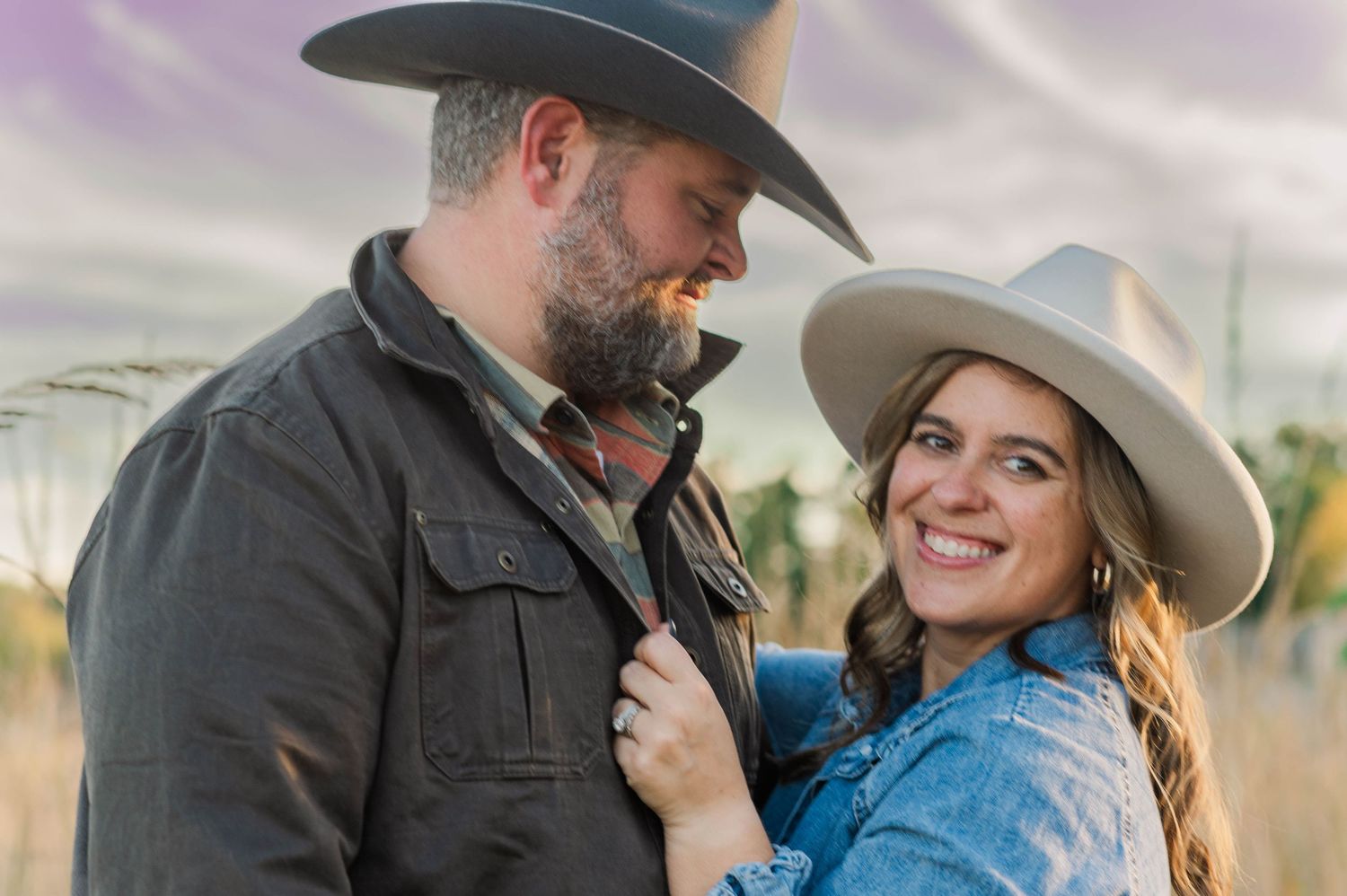 A couple shares intimate moments while wearing western hats during an outdoor photoshoot.