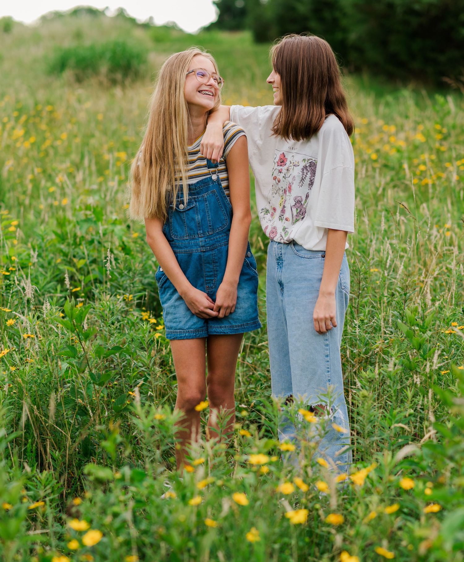 Two children walk through a wildflower meadow on a sunny summer day.