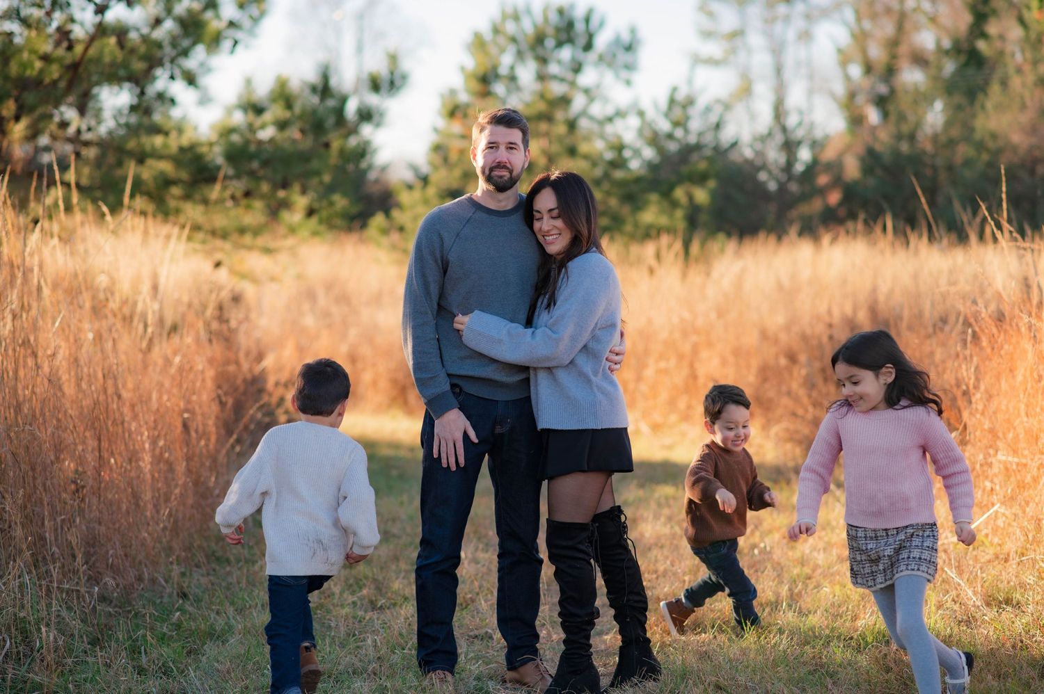 Family enjoying a playful moment together in a golden field at sunset.