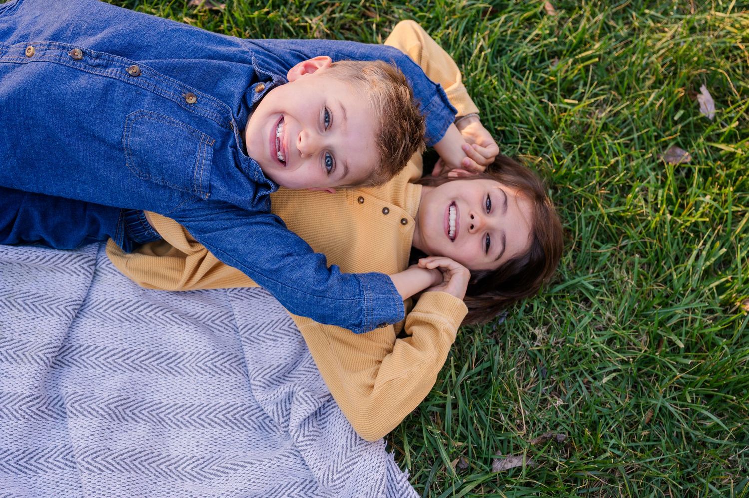 Children laying on grass during an outdoor photo session with natural lighting.