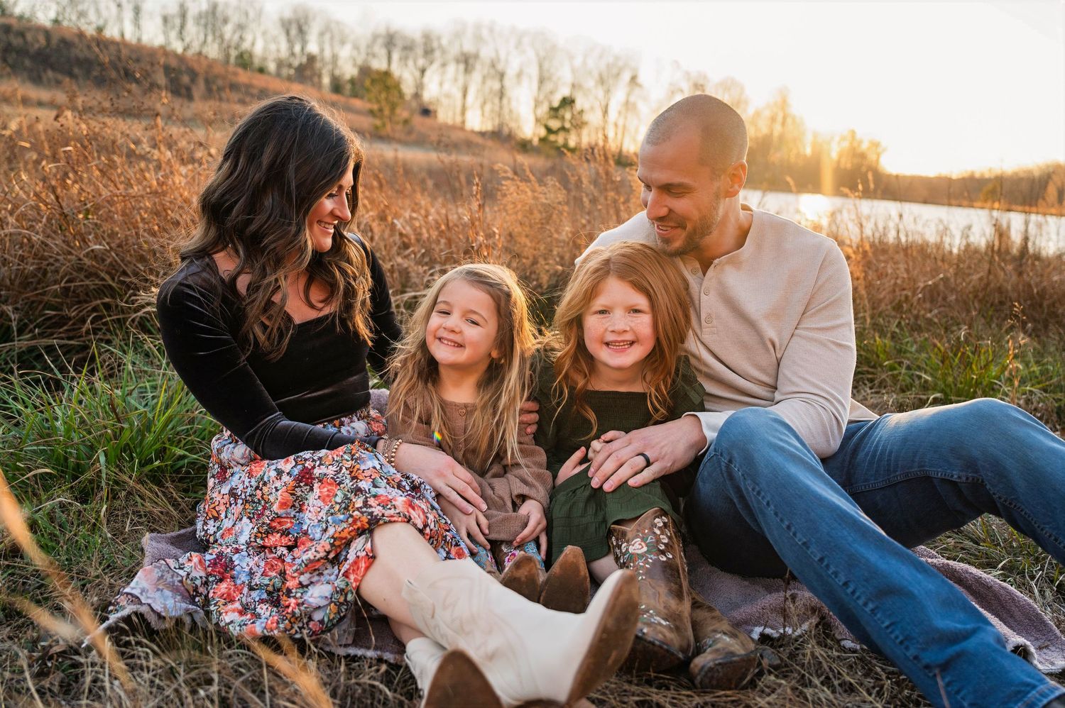 A family enjoys a playful moment together outdoors during golden hour in a rustic field setting.