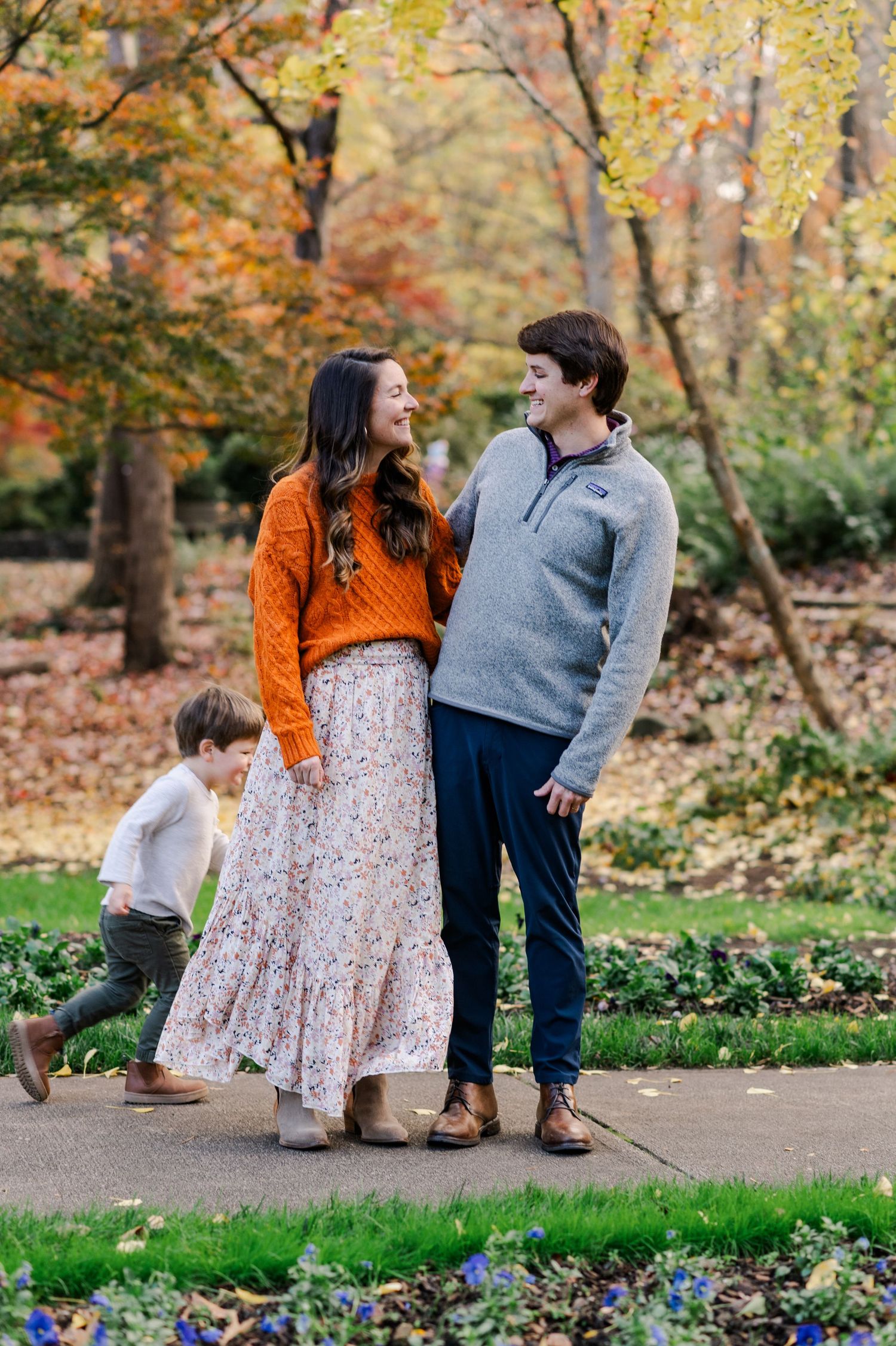 Family playing together among autumn trees with vibrant fall colors.