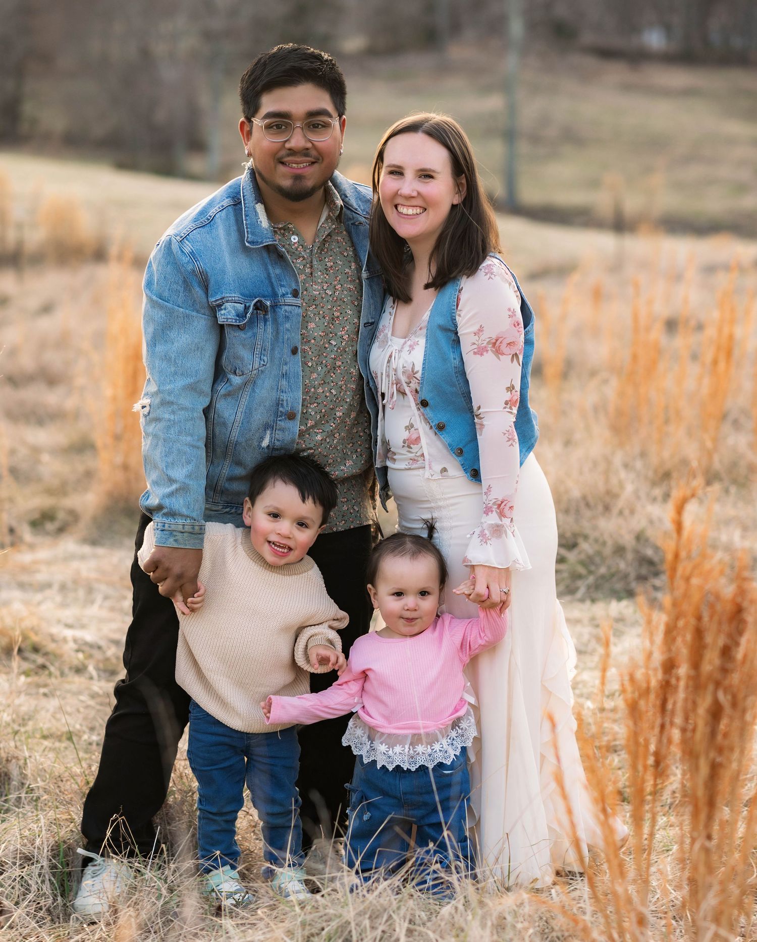 Family enjoying a sunset photoshoot in a field with golden grass and warm lighting.