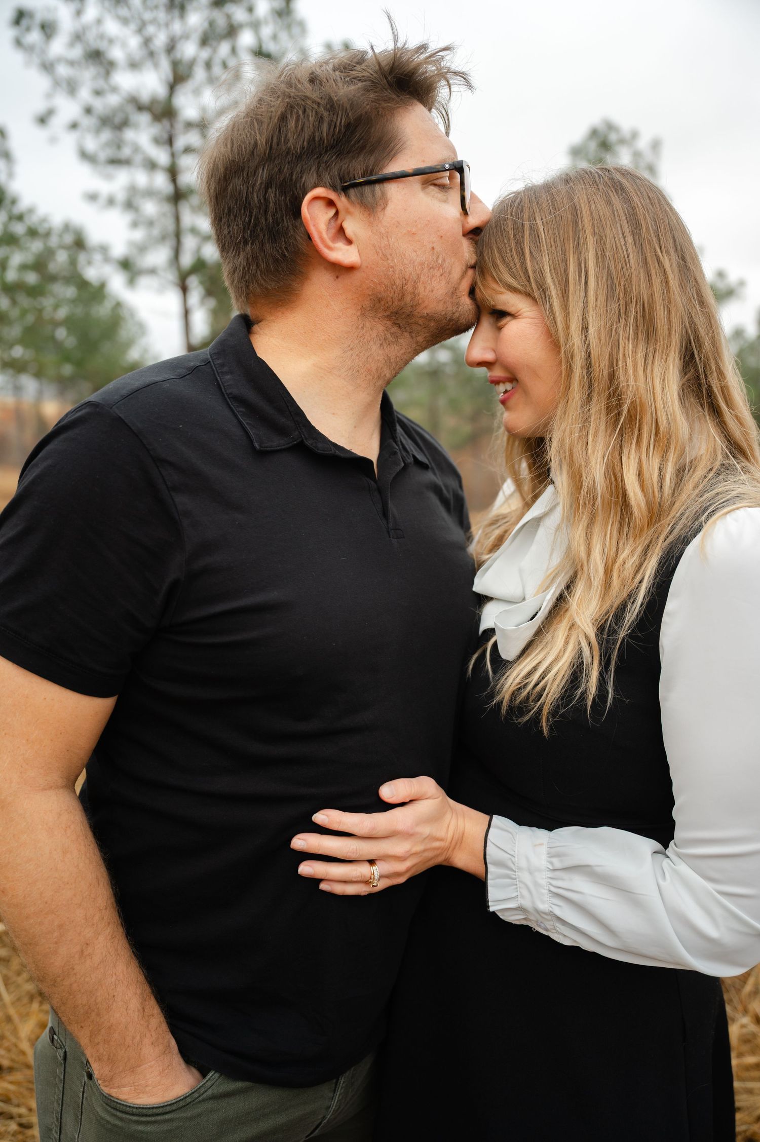 Intimate moment between couple in casual wear against natural outdoor setting.