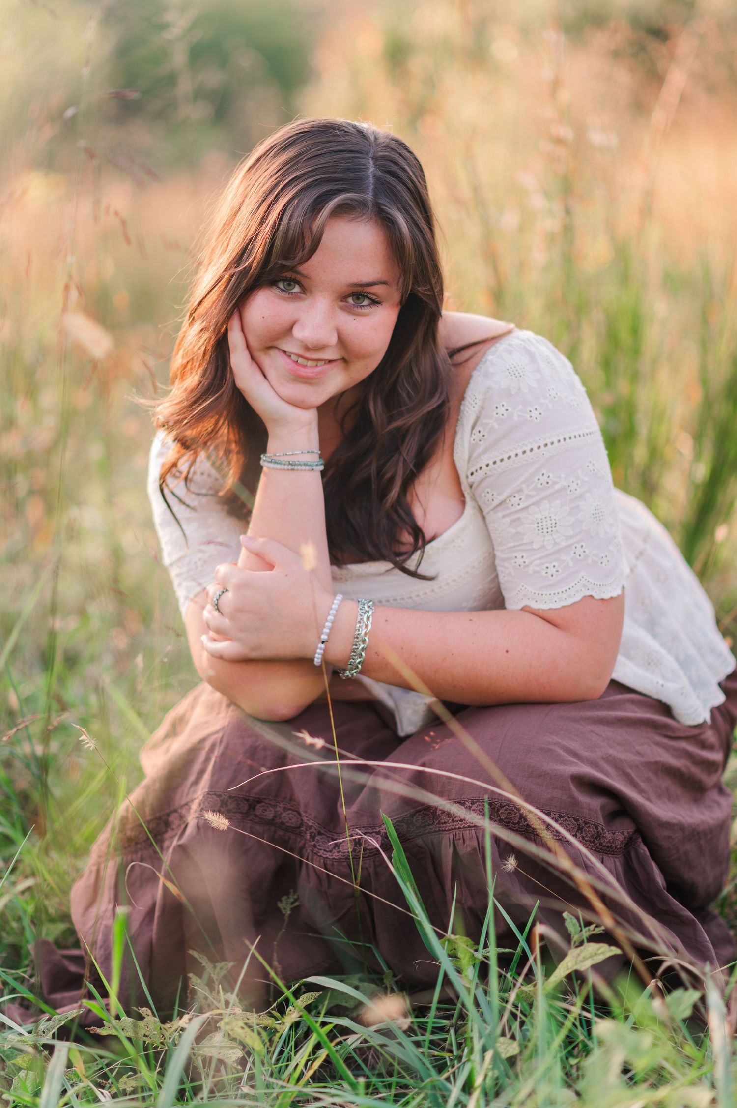 Woman in white dress lying in golden summer grass during outdoor portrait session.