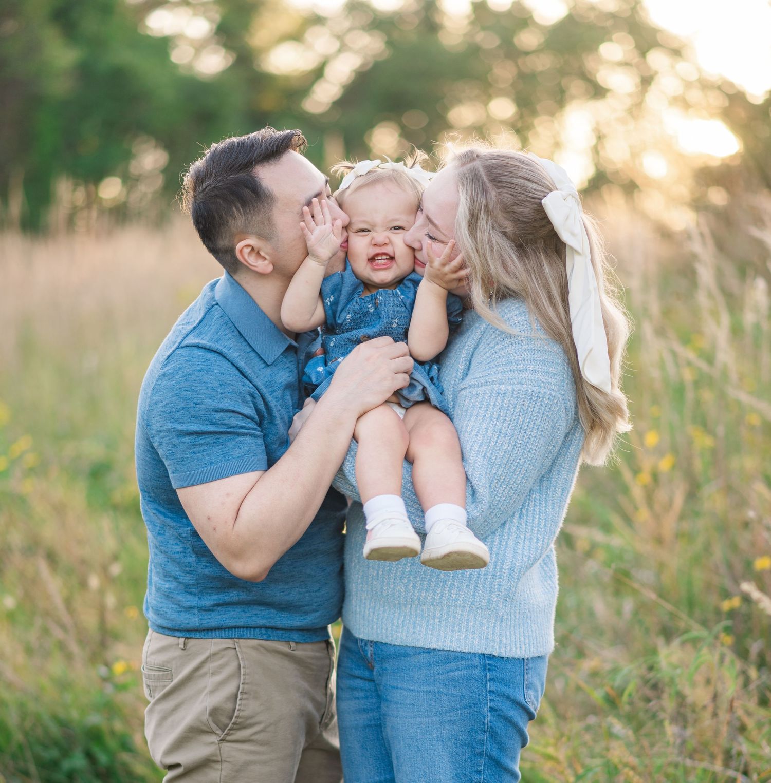 Family sharing tender moment together in field during golden hour sunset.