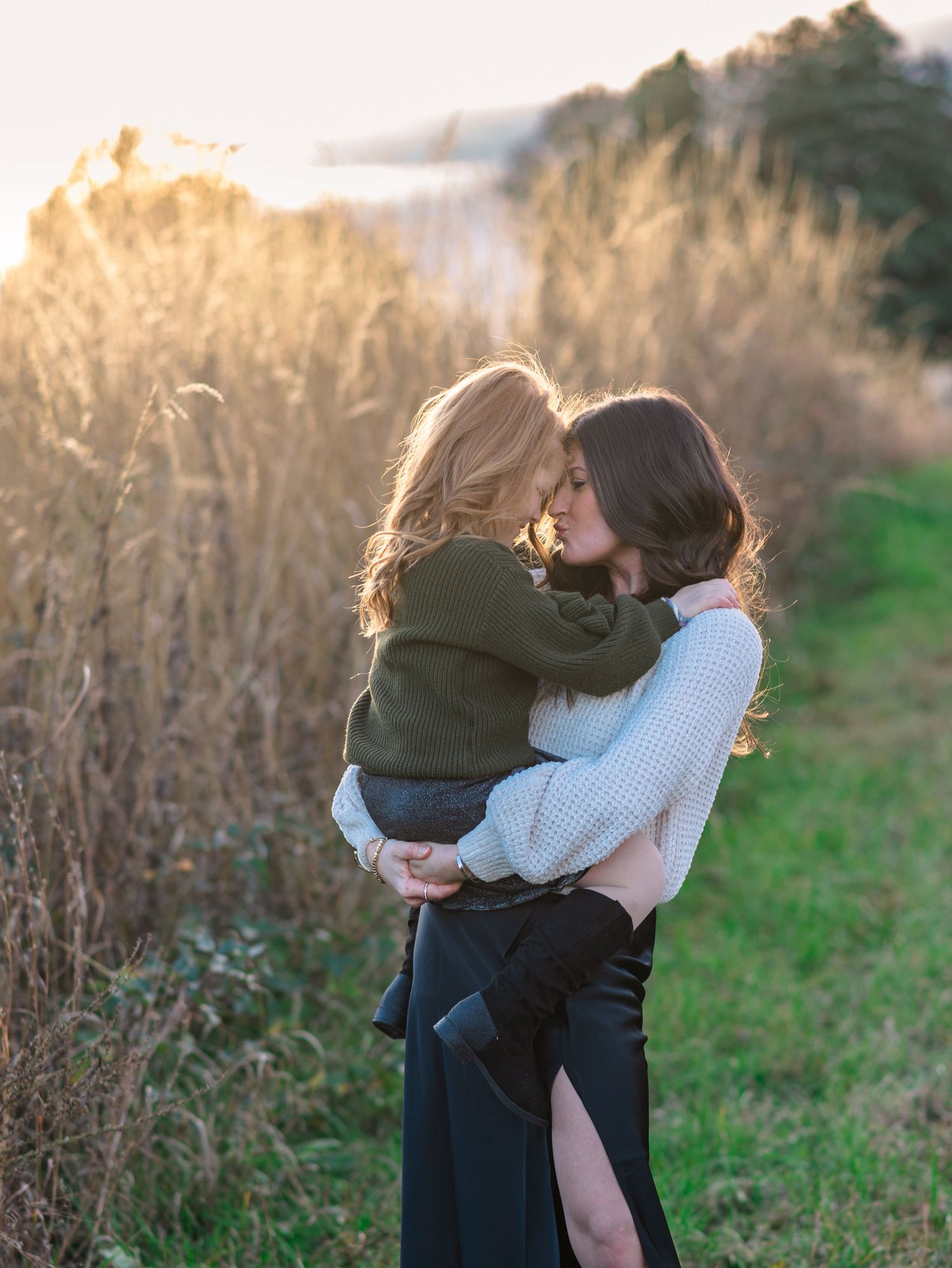 Intimate family embraces captured in a field during golden hour.