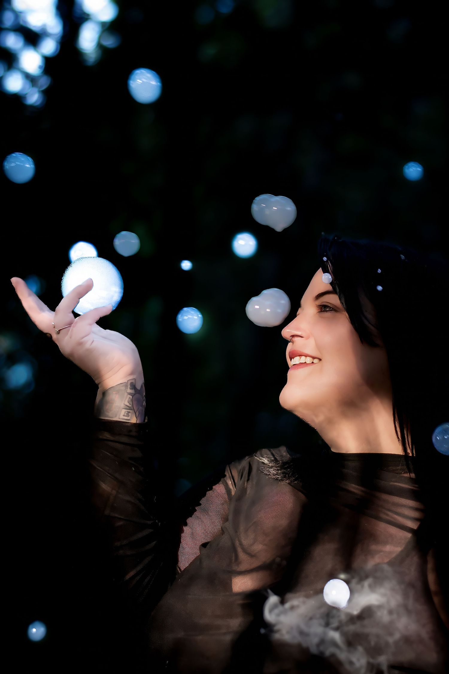 Artistic portrait with bokeh lights and unique fog bubbles in a dark nighttime setting.