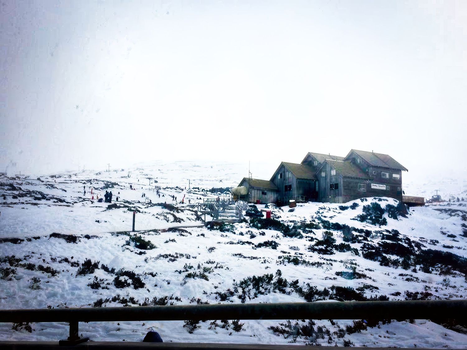 Snow covered buildings in a desolate winter landscape under grey skies.