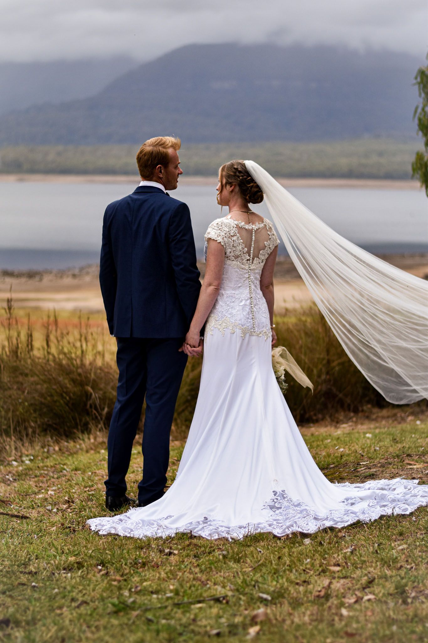 Wedding couple in scenic mountain landscape with flowing white veil.