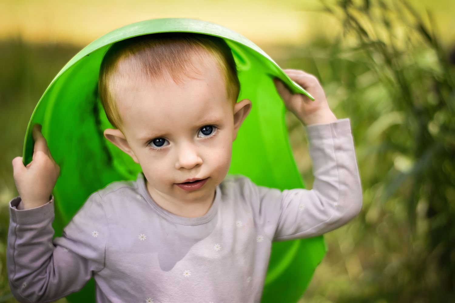 Child playing with bright green garden objects in natural setting.
