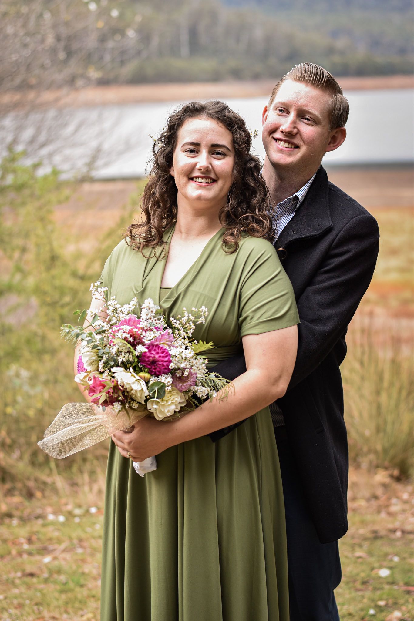 Couple in formal attire holding floral bouquet during outdoor autumn photoshoot.