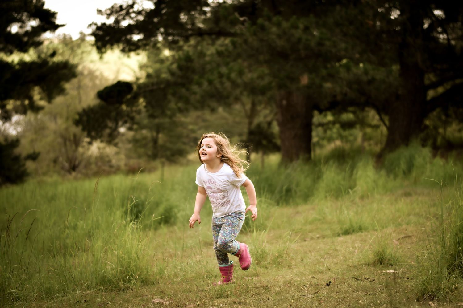 Child running through a grassy field on a sunny autumn day.