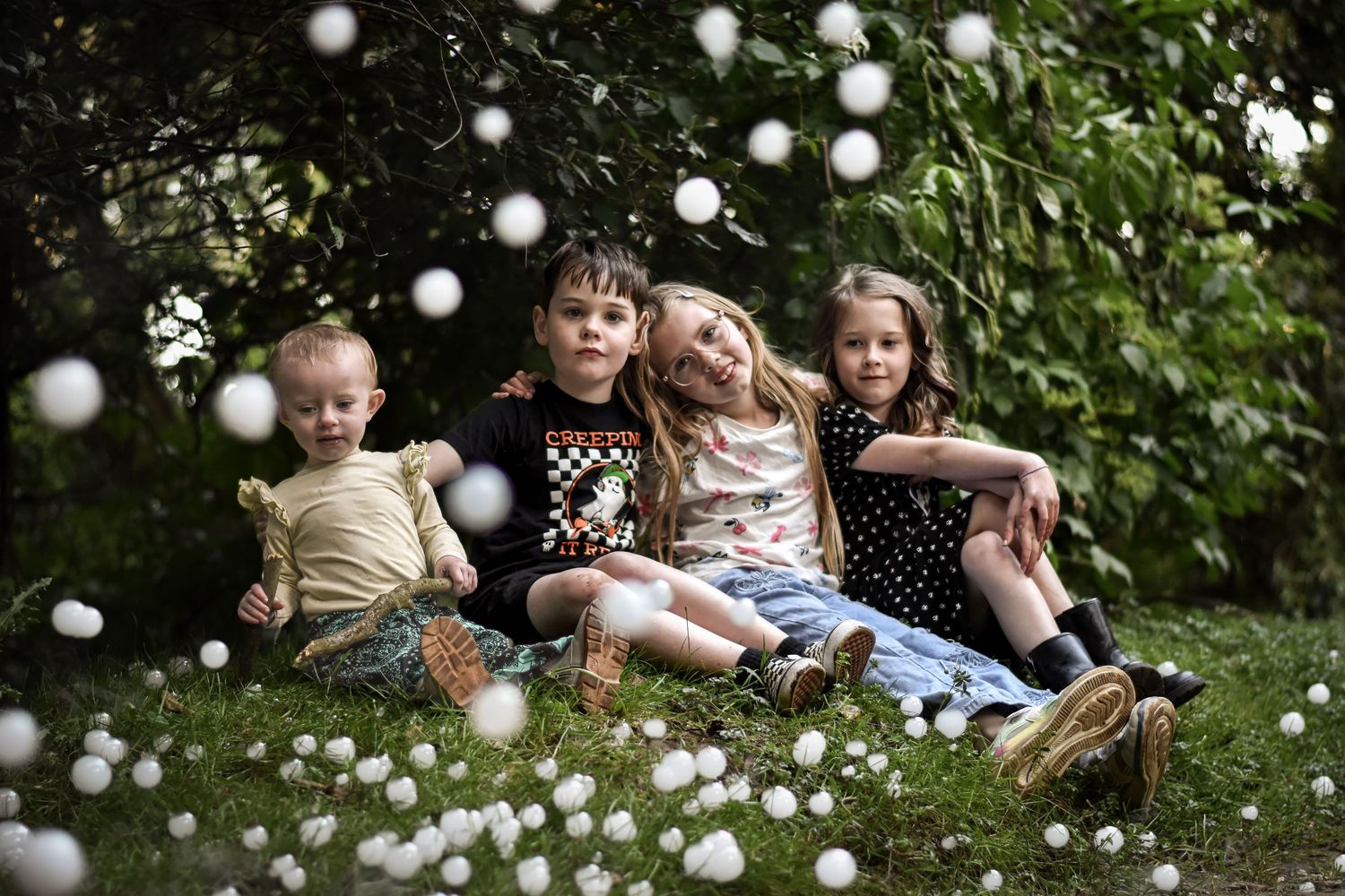 People lying in grass with bubbles floating in the air during an outdoor photo session.