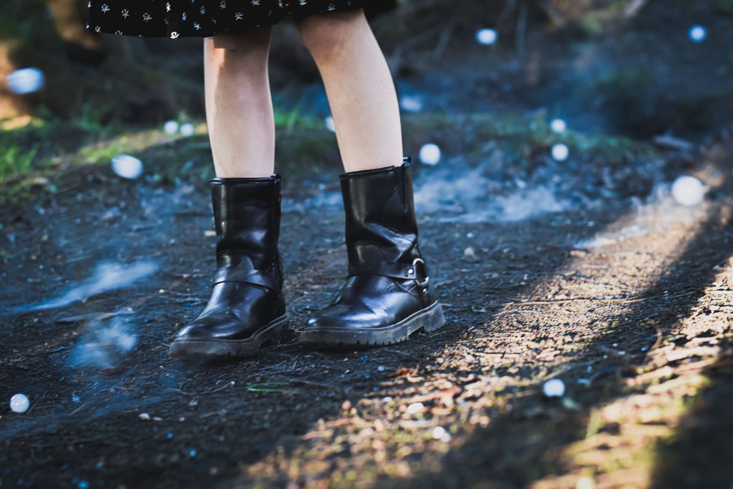 Sparkly water droplets reflecting light around person's boots on gravel path.