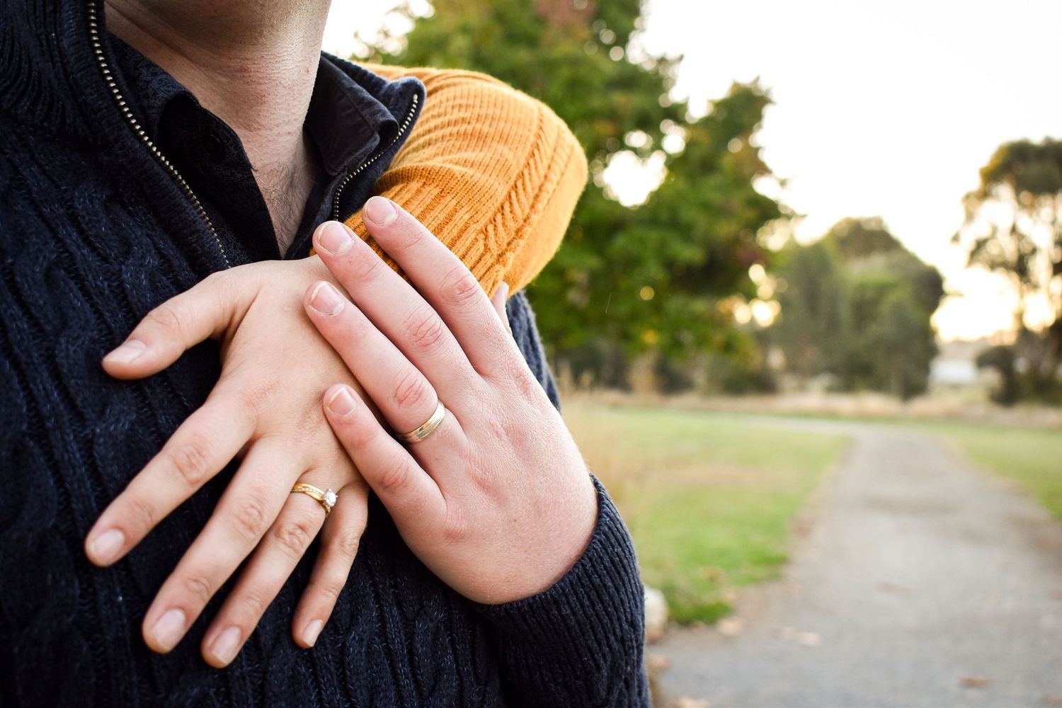 Close up of hands holding ultrasound photo during outdoor pregnancy announcement.
