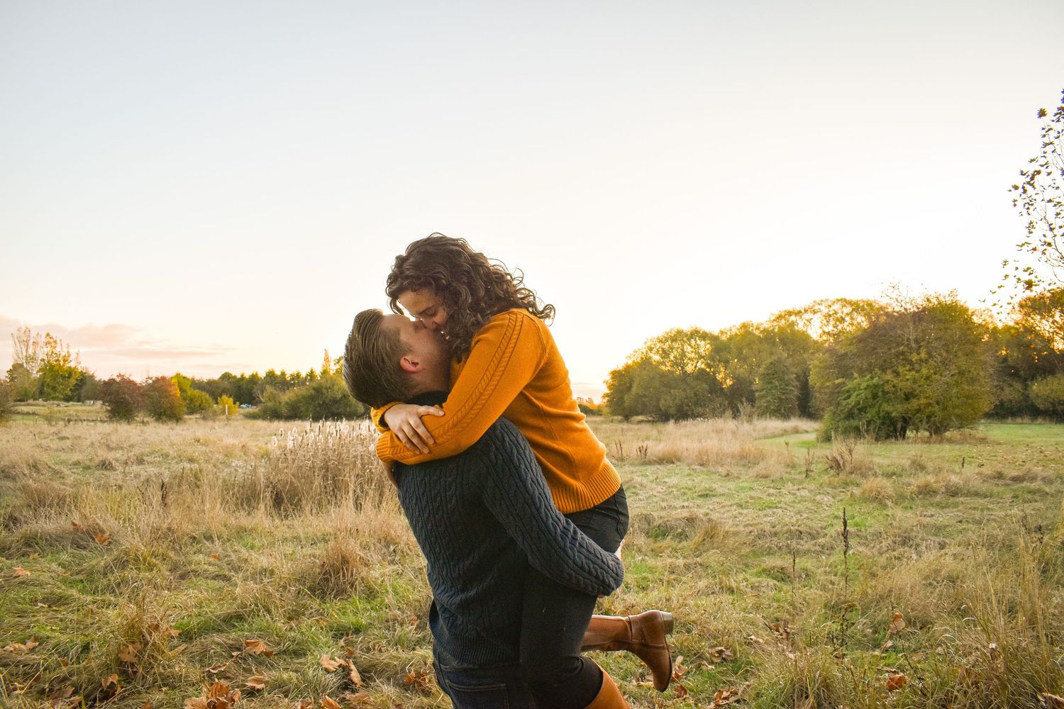 Intimate outdoor portrait session at sunset in a rustic field setting.
