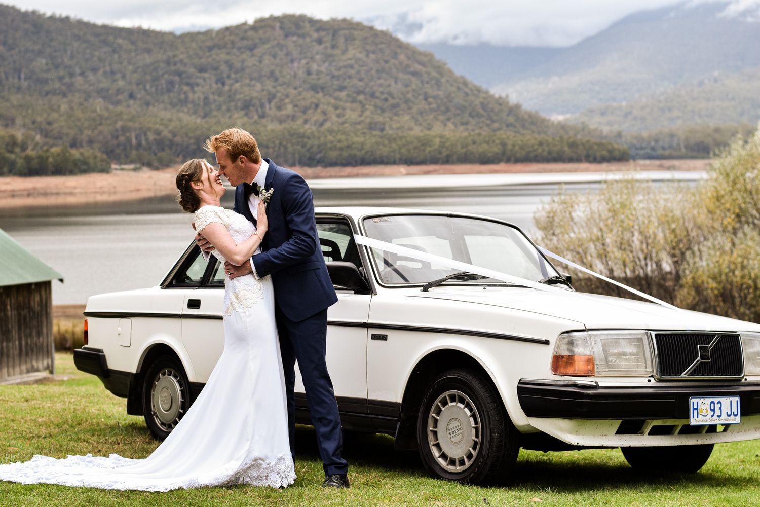 Classic white vintage car parked in mountain landscape with wedding couple.