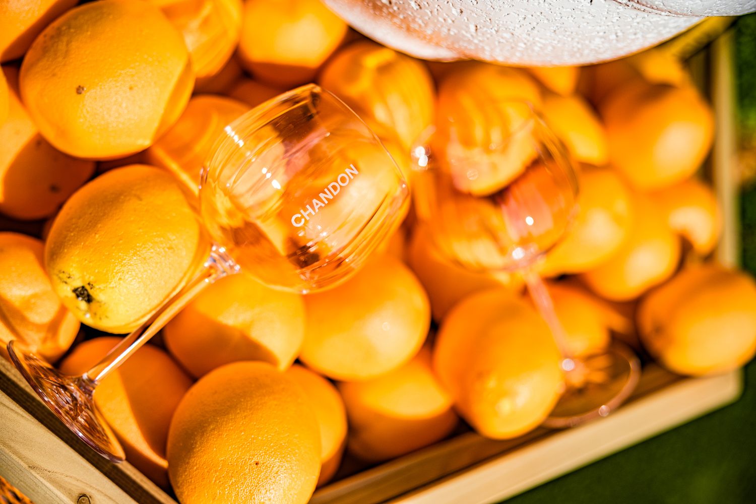 Chandon branded wine glass resting on a crate of fresh golden mangoes at a summer event.