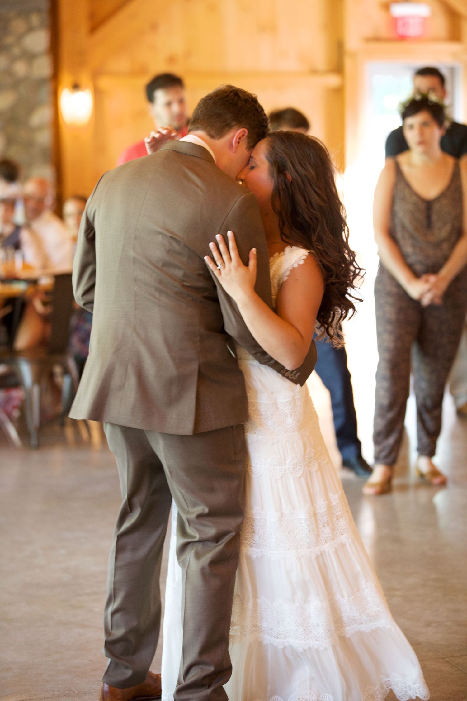 Bride and groom share their first dance kiss in a warmly lit rustic barn reception venue.