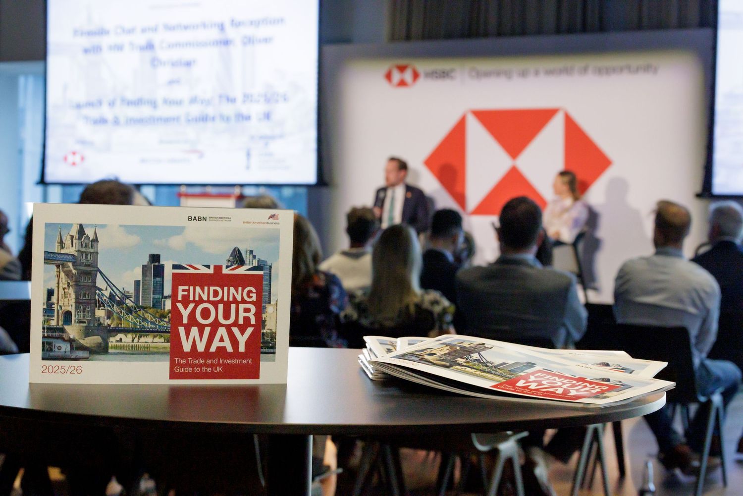 HSBC business seminar with attendees facing a presentation screen, with Finding Your Way guides in foreground.