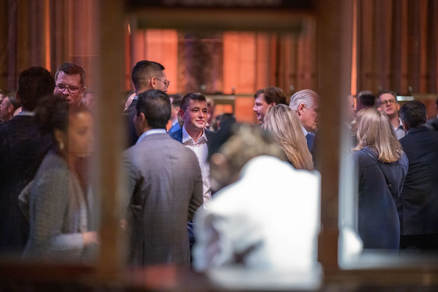 Guests mingling at an upscale networking event inside a warmly lit historic venue.