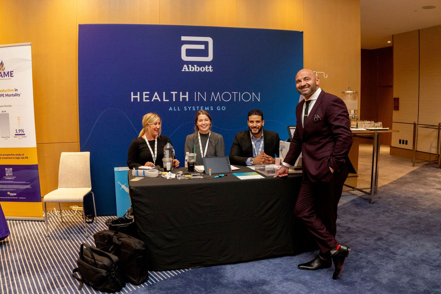 Abbott Health in Motion booth with four smiling professionals posing at a medical conference exhibition.