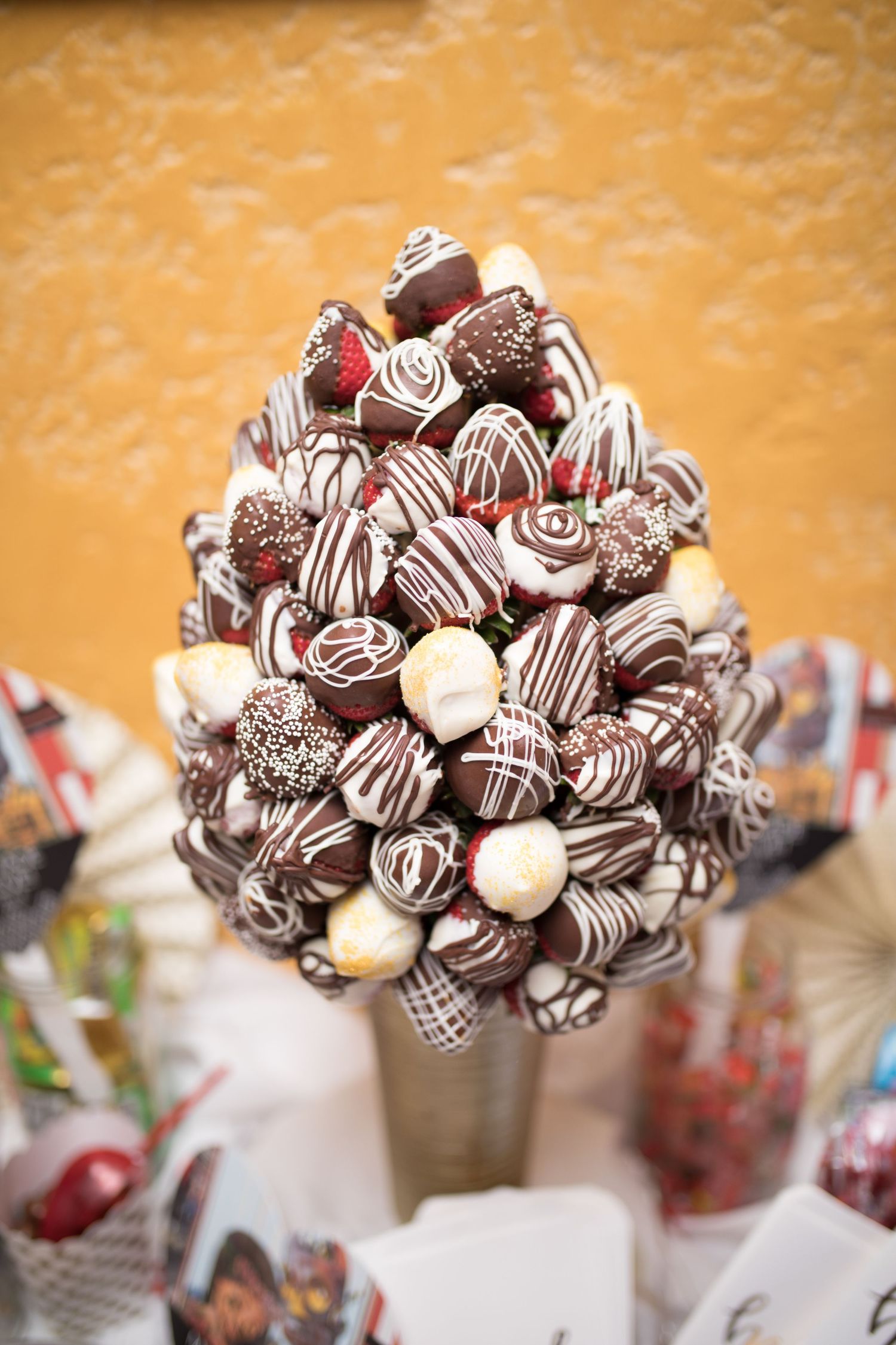 Elegant tower of chocolate-dipped strawberries with white drizzle displayed as wedding dessert centerpiece.