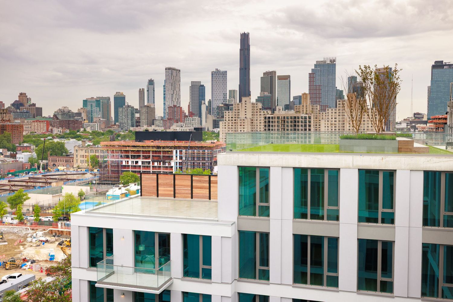 Rooftop terrace of a modern white apartment building with panoramic New York City skyline views.