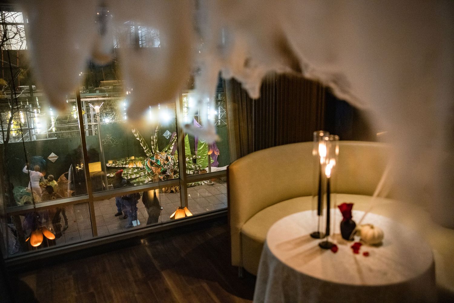 Romantic candlelit table by window overlooking festive outdoor garden gathering.