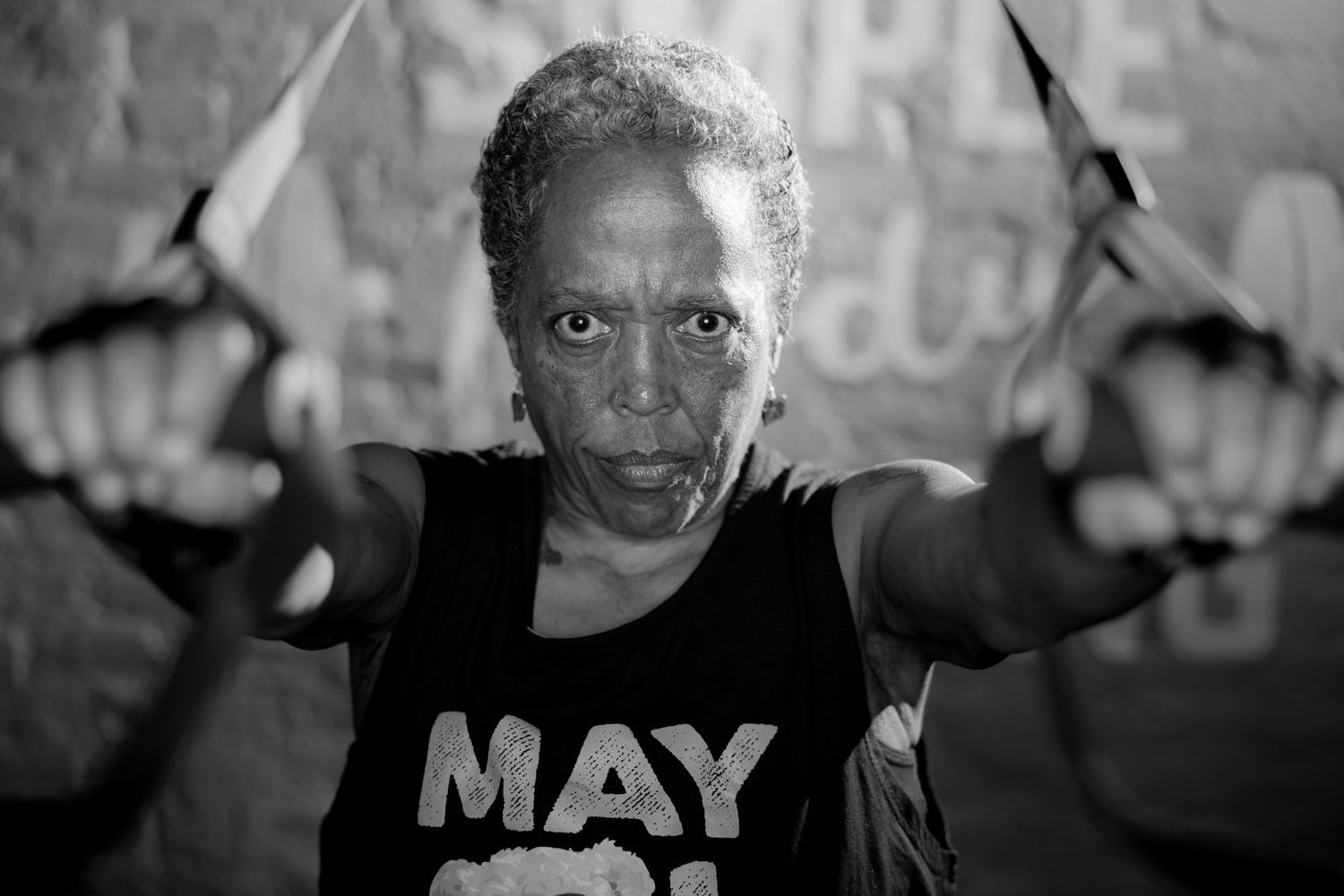 Black and white photo of a determined older woman doing TRX suspension training exercises at a gym.