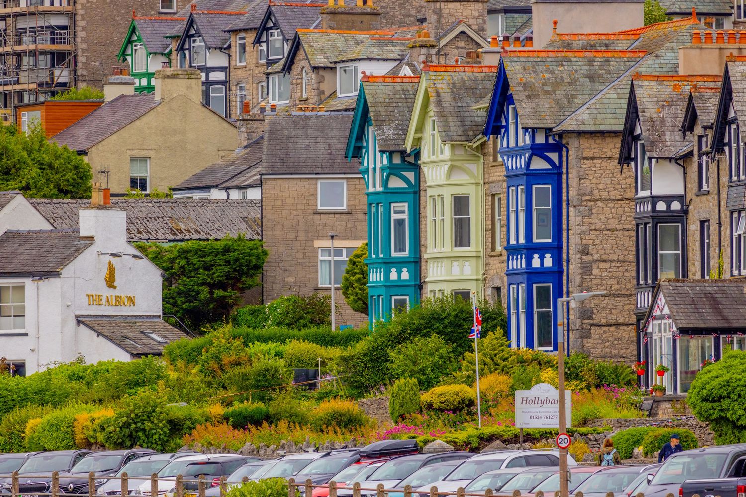 Colorful Victorian terraced houses in teal blue and green overlooking a coastal town car park in Wales.