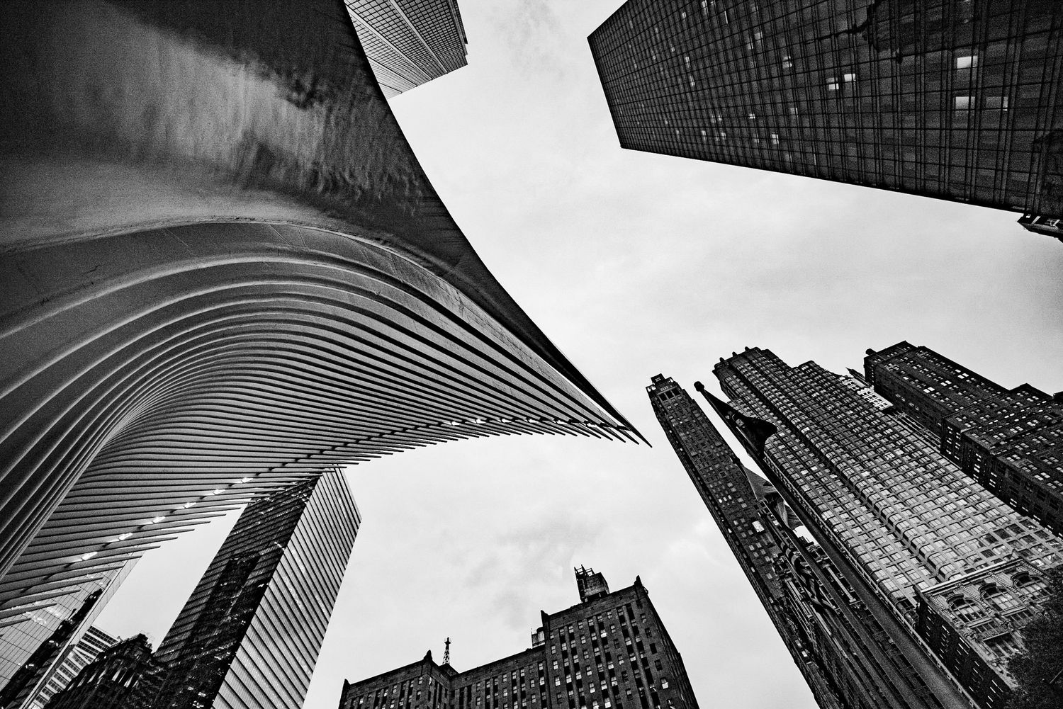 Black and white worm's-eye view of Manhattan skyscrapers including the Oculus and One World Trade Center.
