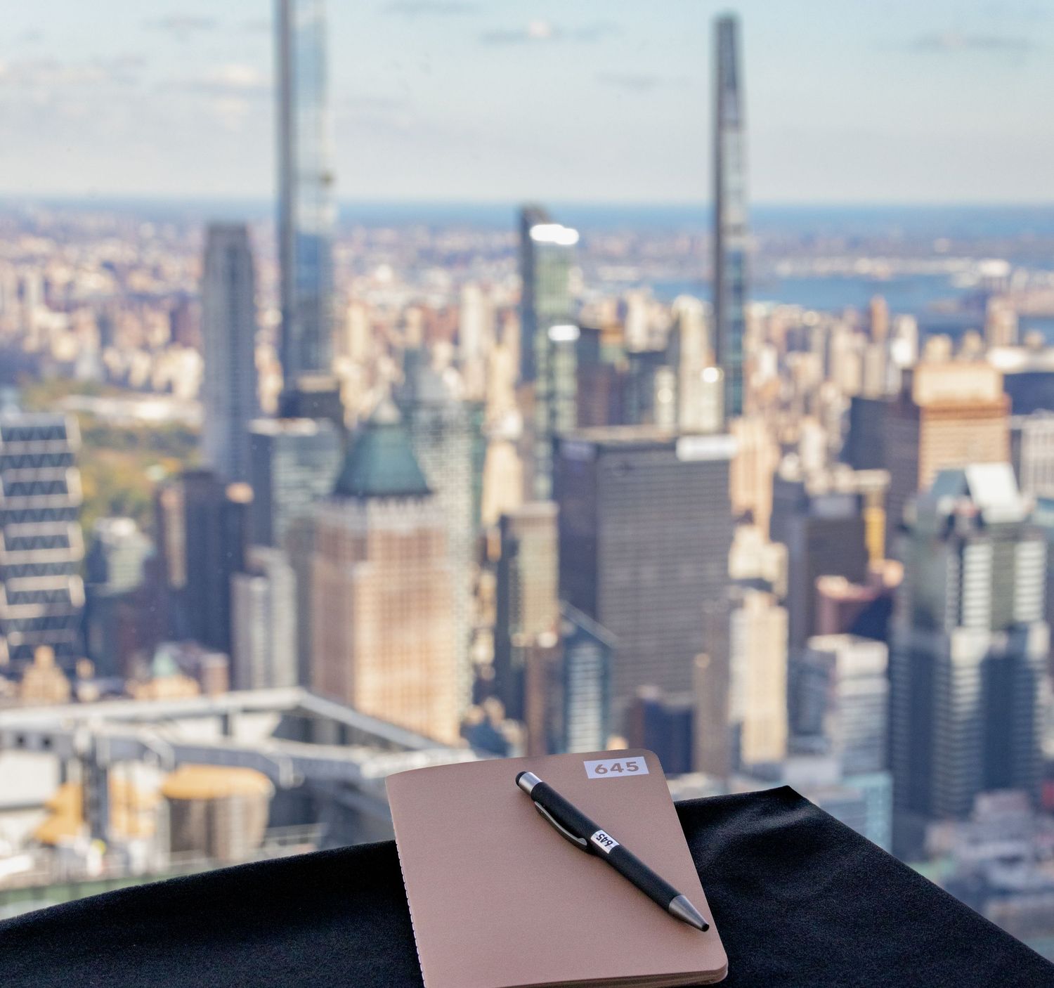 Notebook and pen on table with New York City skyline in the background.