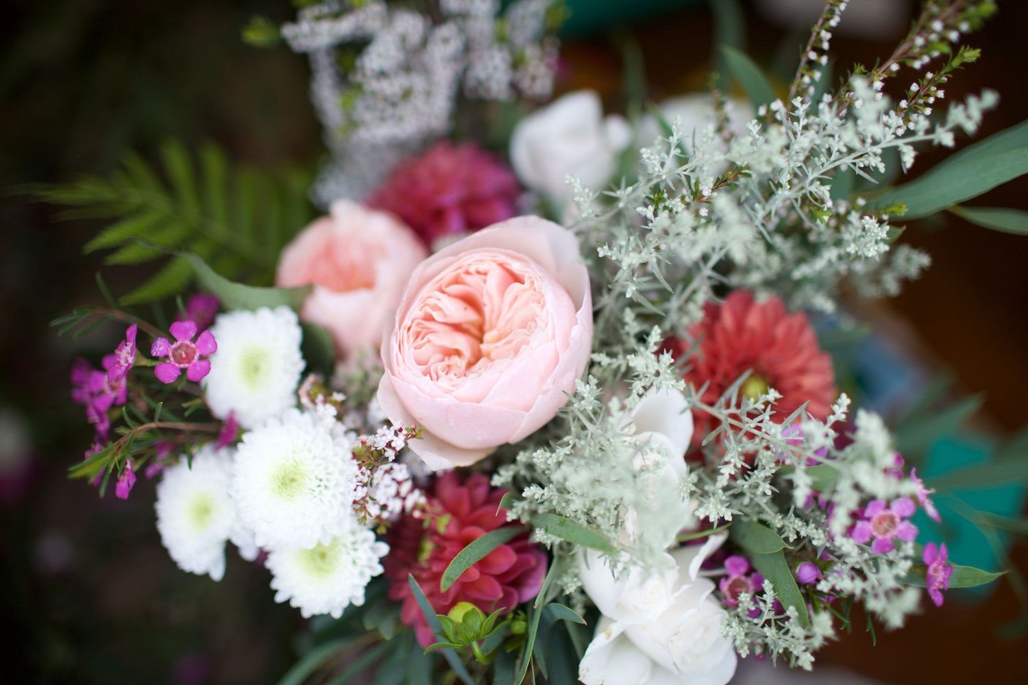 Close-up of elegant bridal bouquet featuring pink garden roses, white daisies, and wildflowers.