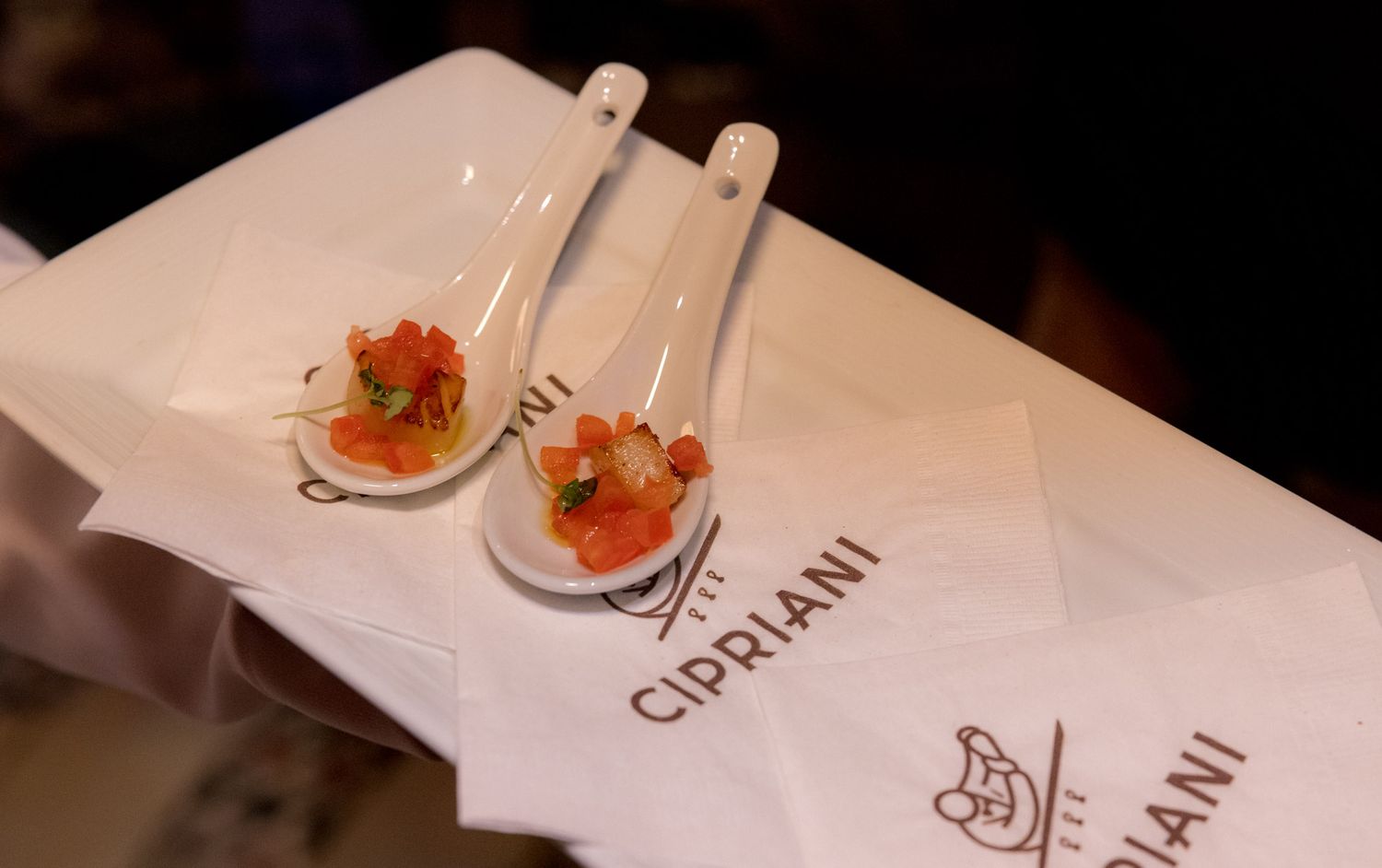 Two elegant white spoons with salmon appetizers on Cipriani branded linen napkins.