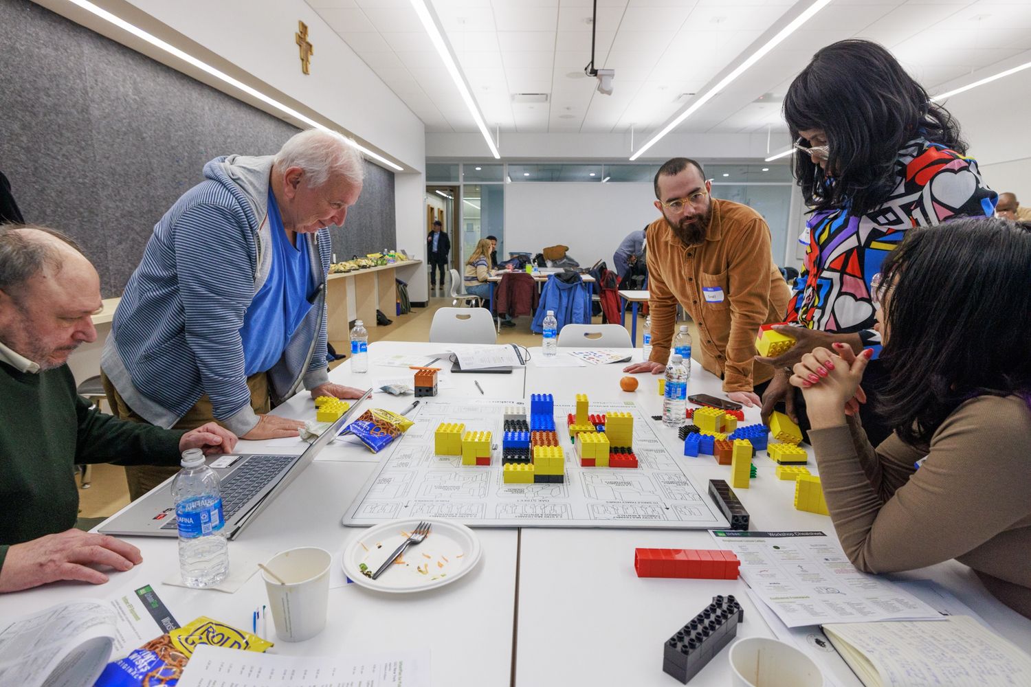 Diverse participants collaborate around a table with colorful LEGO bricks in a workshop setting.