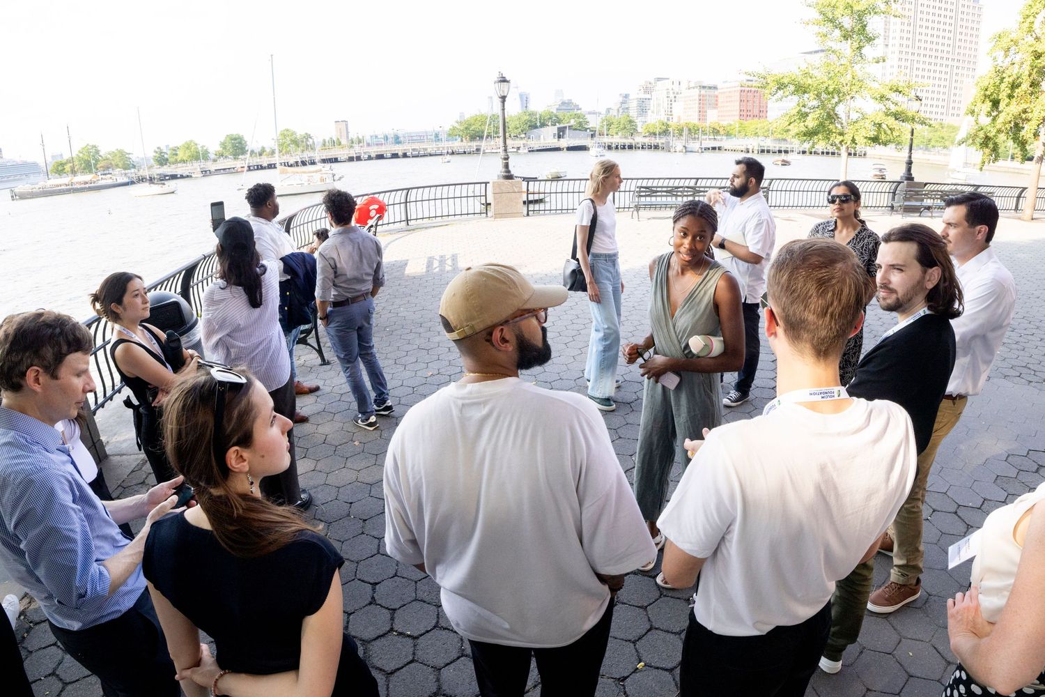 Diverse group of young professionals networking in an outdoor waterfront discussion circle.
