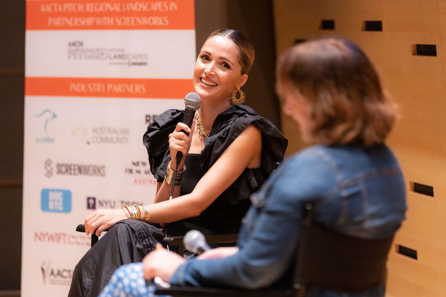 Woman smiling and speaking into microphone during a panel discussion at a film industry conference event.
