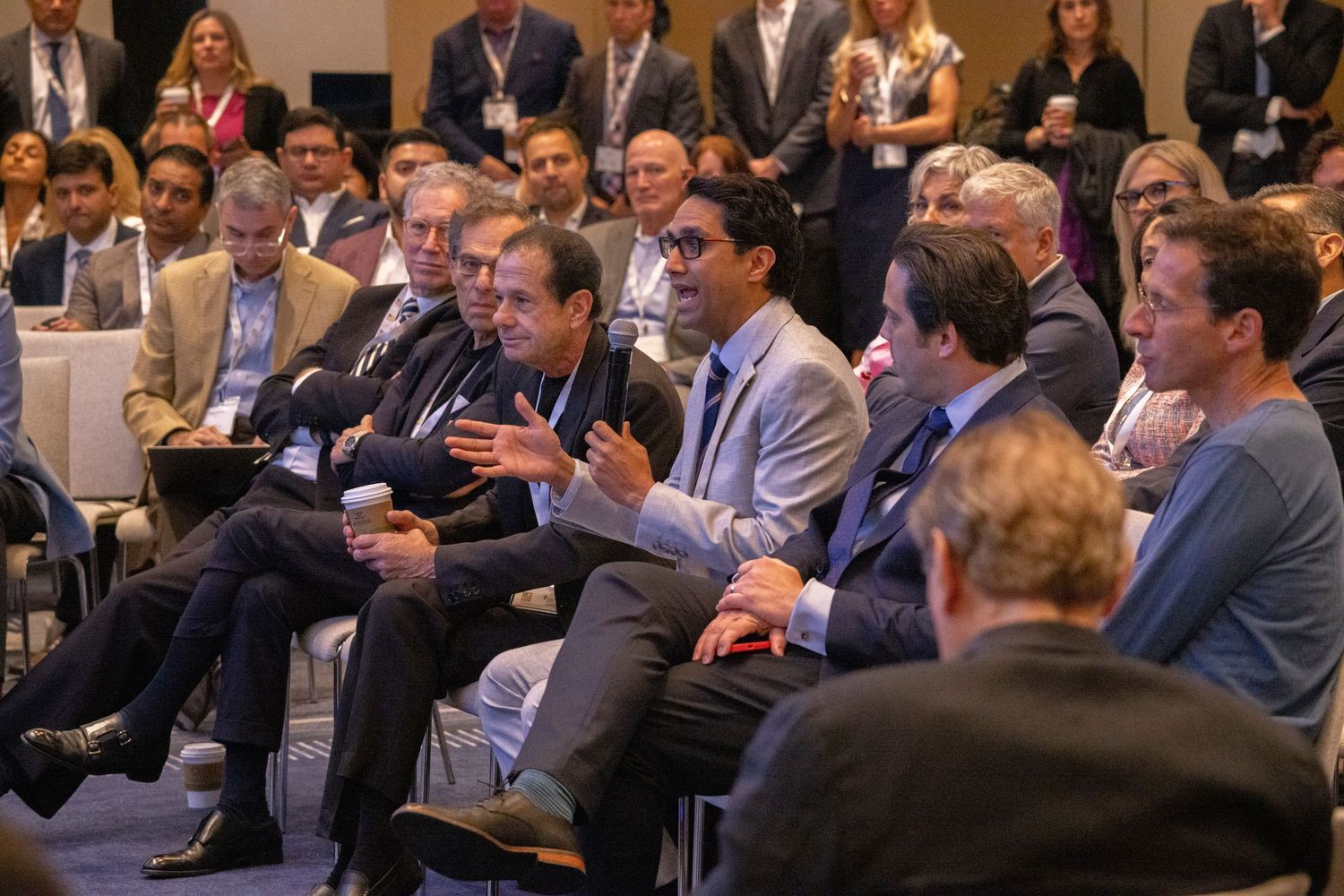 Business professionals engaged in discussion at a corporate conference, seated in rows at a formal networking event.