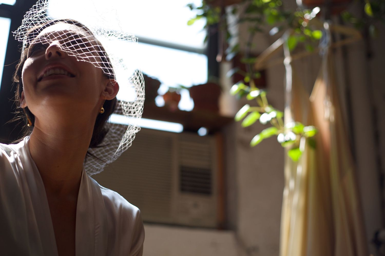 Bride wearing a delicate birdcage veil with eyes closed in soft natural sunlight.