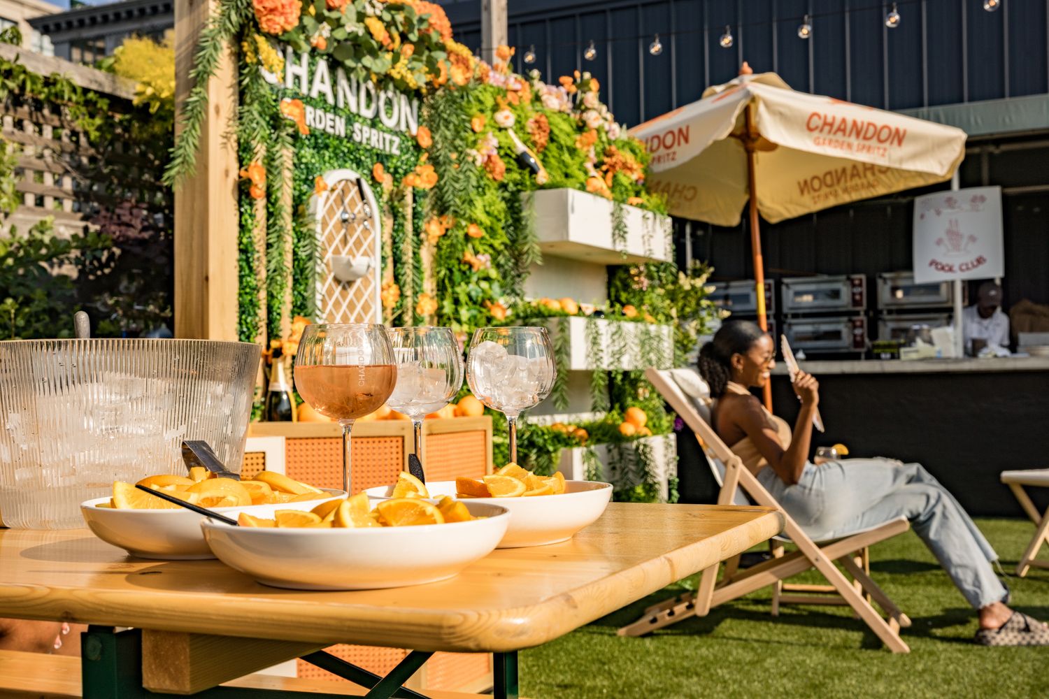 Chandon champagne brand outdoor lounge setup with food, drinks, and a relaxing woman in a deck chair.