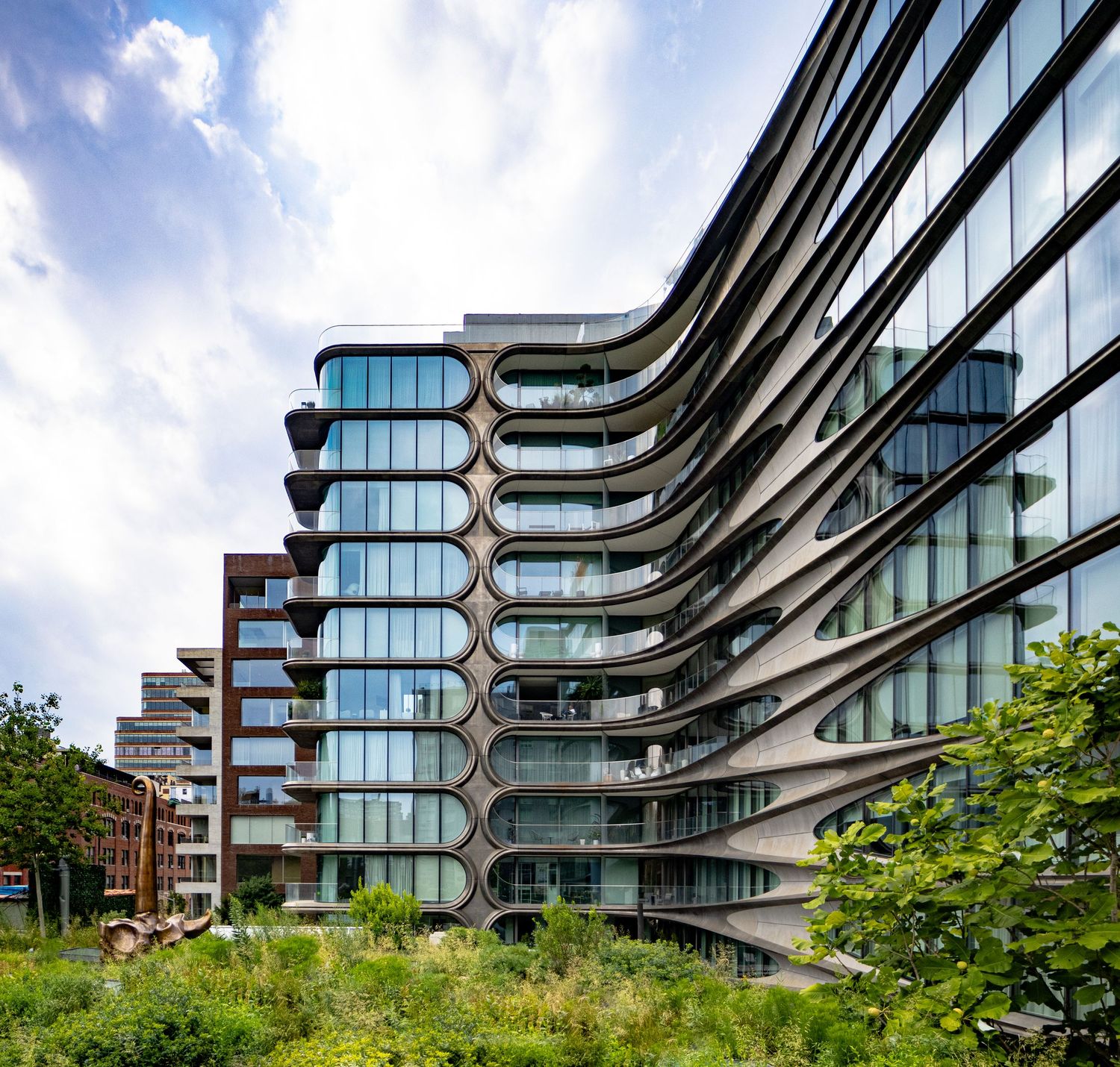 Residential building with sweeping curved balconies and glass facade viewed from the High Line.